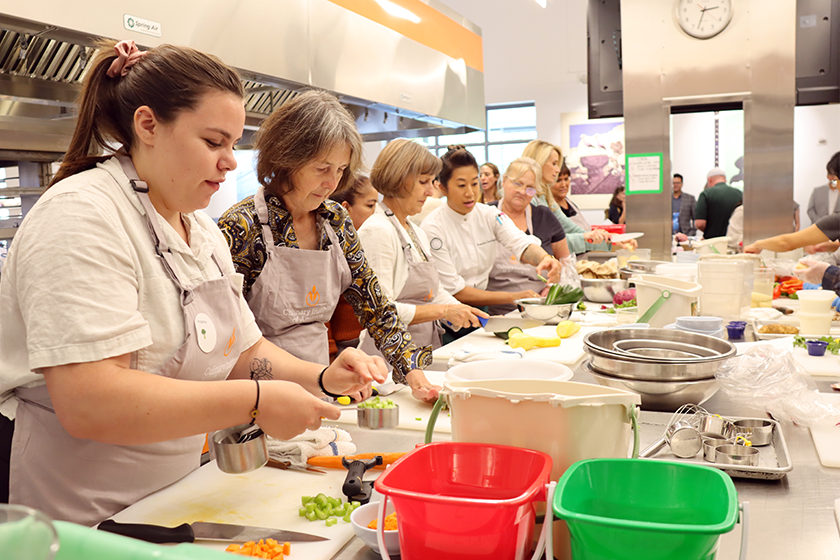 Senator Nancy Skinner practices knife skills with school nutrition staff. 