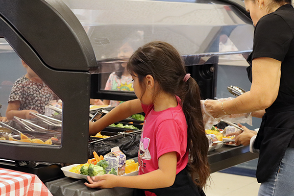 A student fills their lunch tray